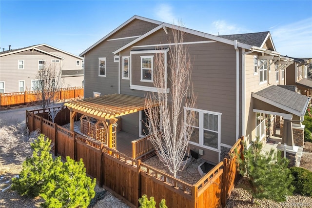 back of house featuring a shingled roof, a pergola, and fence