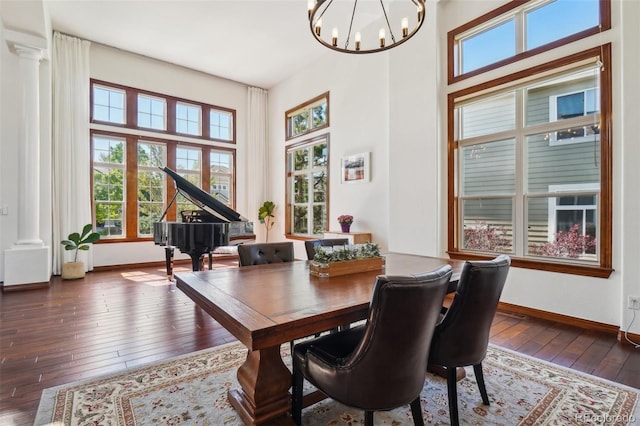 dining space with plenty of natural light, wood-type flooring, decorative columns, and a towering ceiling