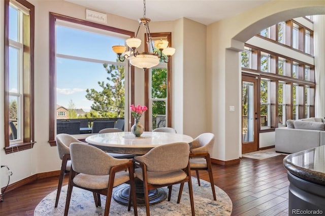 dining space featuring arched walkways, baseboards, and plenty of natural light