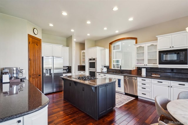 kitchen with black appliances, a kitchen island, glass insert cabinets, white cabinets, and dark wood-style floors