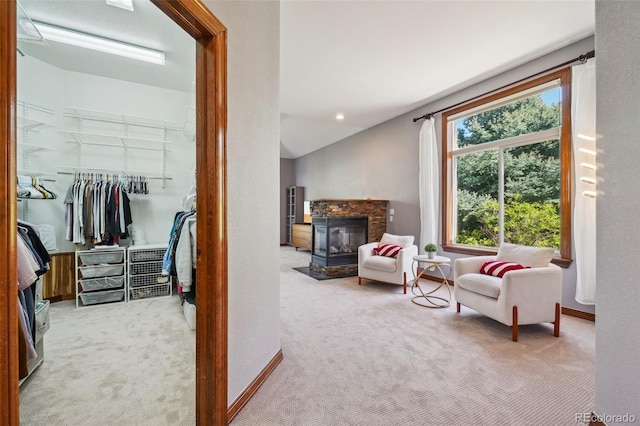living area featuring carpet flooring, a stone fireplace, and baseboards