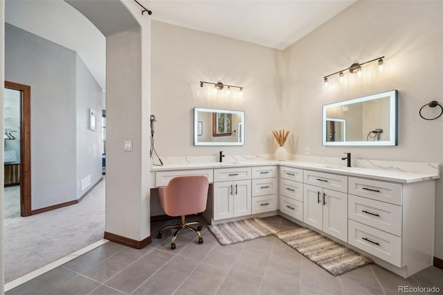bathroom with double vanity, tile patterned flooring, baseboards, and vaulted ceiling
