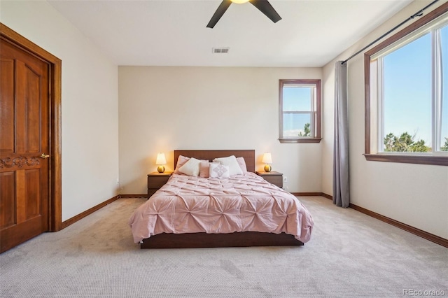 bedroom featuring light colored carpet, baseboards, and a ceiling fan