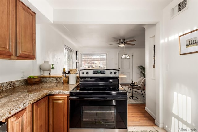 kitchen with light tile patterned flooring, light stone counters, ceiling fan, and stainless steel electric range