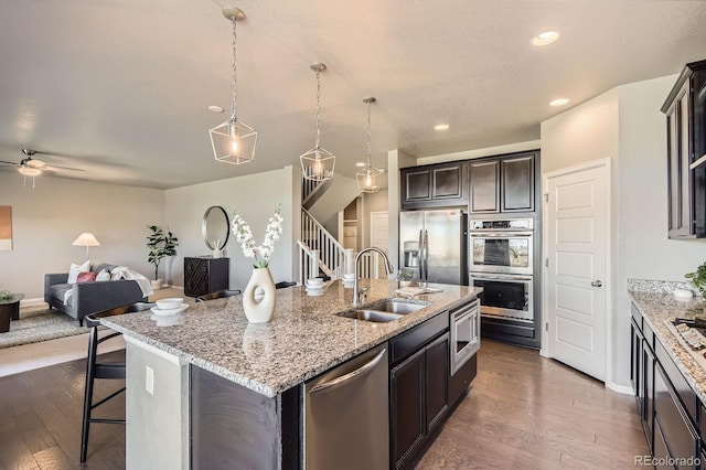 4406 Sidewinder Loop, Castle Rock, CO 80108 - kitchen featuring a sink, appliances with stainless steel finishes, dark wood-style floors, open floor plan, and a kitchen island with sink