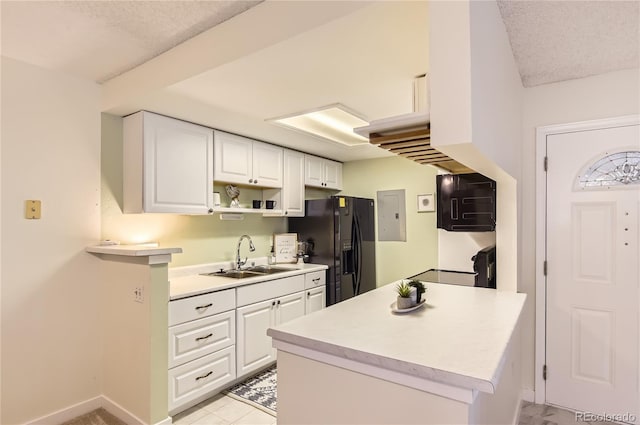 kitchen with a sink, a textured ceiling, black fridge with ice dispenser, white cabinetry, and light countertops