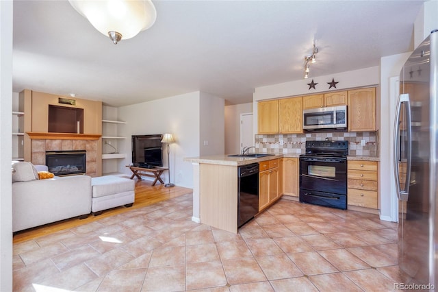 kitchen featuring black appliances, tasteful backsplash, sink, kitchen peninsula, and a tiled fireplace