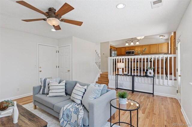 17611 Hoyt Pl, Parker, CO 80134 - living room featuring light wood finished floors, baseboards, stairs, ceiling fan, and a textured ceiling