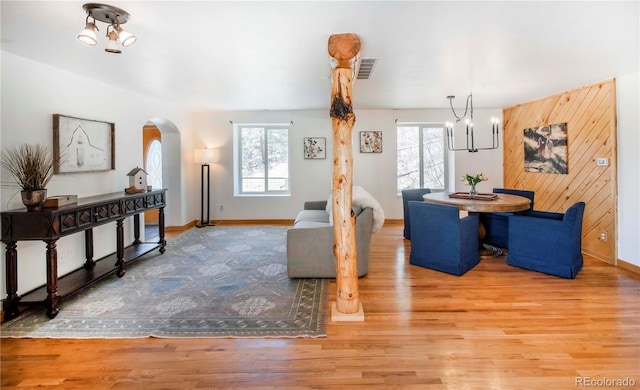 dining area featuring arched walkways, a wealth of natural light, wood finished floors, and visible vents