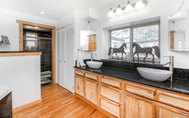 bathroom featuring a closet, a sink, wood finished floors, and a shower stall