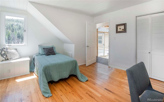 bedroom with baseboards, light wood-style flooring, and a closet
