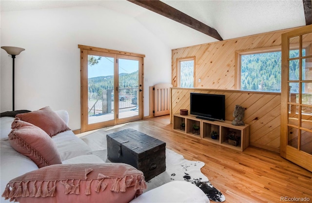 living area featuring wooden walls, vaulted ceiling with beams, and wood finished floors