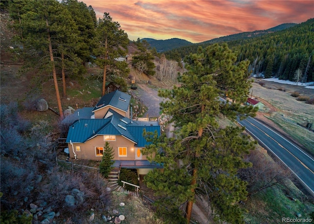 aerial view at dusk featuring a wooded view and a mountain view