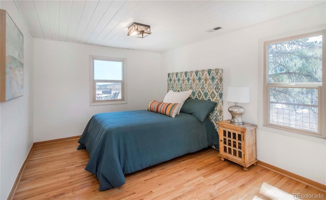 bedroom with baseboards, visible vents, and light wood finished floors