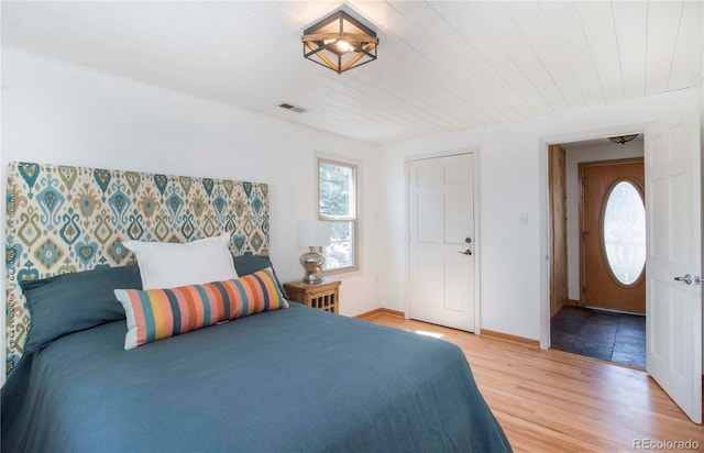 bedroom with baseboards, wood ceiling, light wood-style flooring, and visible vents