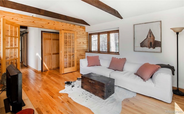 living room featuring baseboards, lofted ceiling with beams, and light wood-style flooring