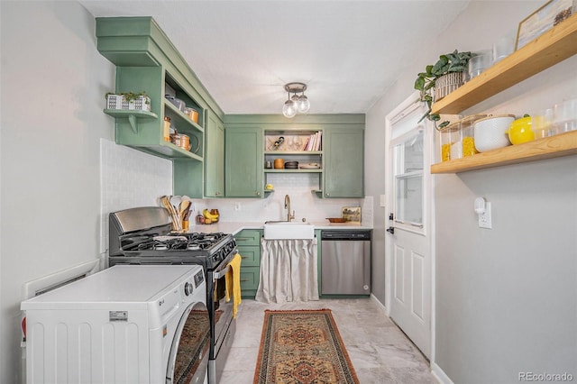 kitchen featuring appliances with stainless steel finishes, tasteful backsplash, washer / dryer, sink, and green cabinetry