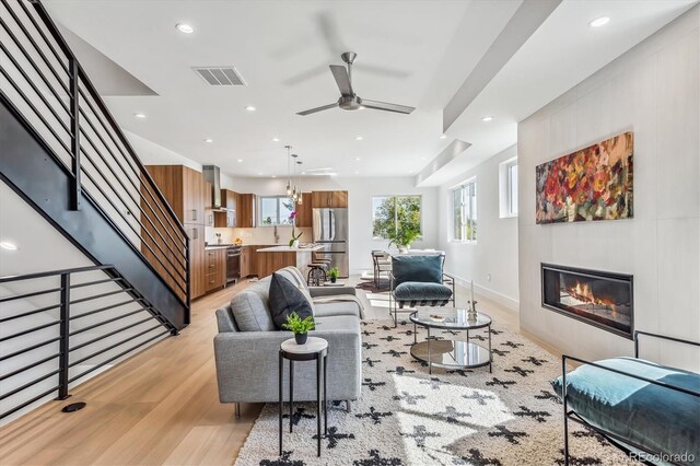 living room with light wood-type flooring and ceiling fan