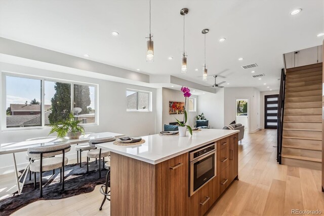 kitchen with pendant lighting, a kitchen island, light wood-type flooring, and ceiling fan