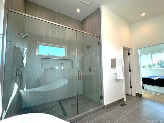 bathroom featuring tile patterned flooring, plenty of natural light, and a shower with shower door