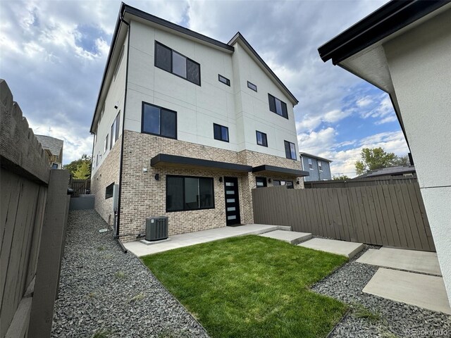 rear view of house with cooling unit, a patio, and a lawn