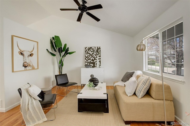 living area with wood finished floors, lofted ceiling, baseboards, and ceiling fan