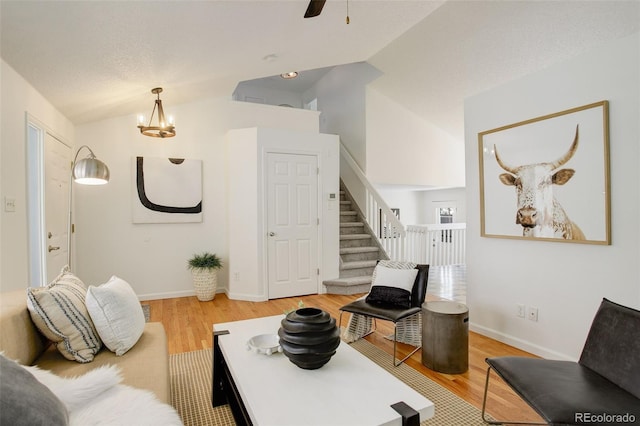 living area with lofted ceiling, baseboards, light wood-style floors, and stairs