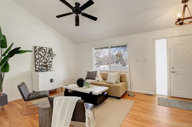 living area with ceiling fan, lofted ceiling, light wood-style floors, and baseboards