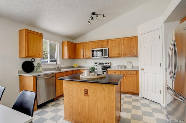 kitchen with light floors, a sink, a center island, a textured ceiling, and appliances with stainless steel finishes