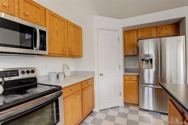 kitchen featuring light countertops, appliances with stainless steel finishes, brown cabinets, and light floors