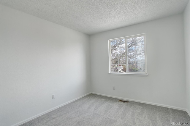 spare room with baseboards, a textured ceiling, visible vents, and carpet