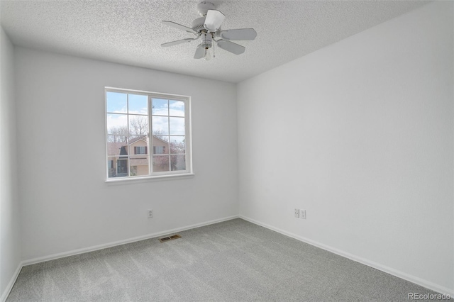 spare room featuring a textured ceiling, carpet floors, visible vents, and a ceiling fan