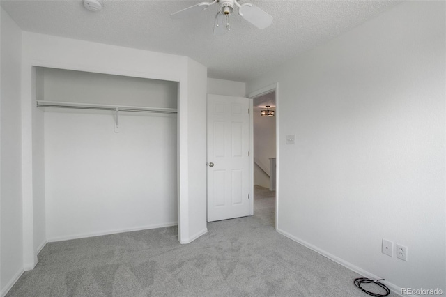 unfurnished bedroom with a textured ceiling, a closet, ceiling fan, carpet floors, and baseboards