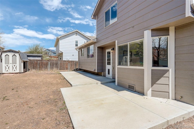 exterior space with a shed, visible vents, fence, an outbuilding, and a patio