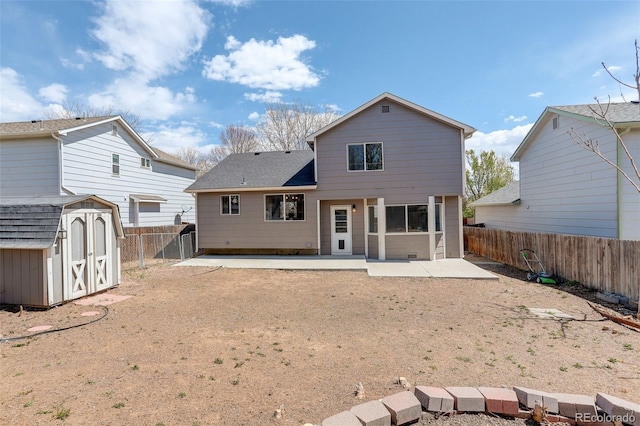 rear view of property featuring a storage shed, an outbuilding, roof with shingles, a fenced backyard, and a patio area