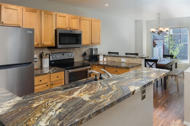 77 Spyglass Ln Unit 77, Silverthorne, CO 80498 - kitchen with appliances with stainless steel finishes, a peninsula, light wood-style flooring, a chandelier, and recessed lighting