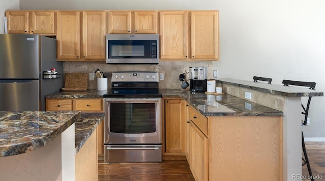77 Spyglass Ln Unit 77, Silverthorne, CO 80498 - kitchen featuring appliances with stainless steel finishes, a peninsula, dark wood-type flooring, decorative backsplash, and dark stone countertops