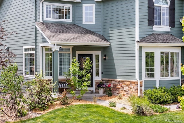 10802 W Indore Dr, Littleton, CO 80127 - doorway to property featuring a shingled roof, stone siding, and a lawn