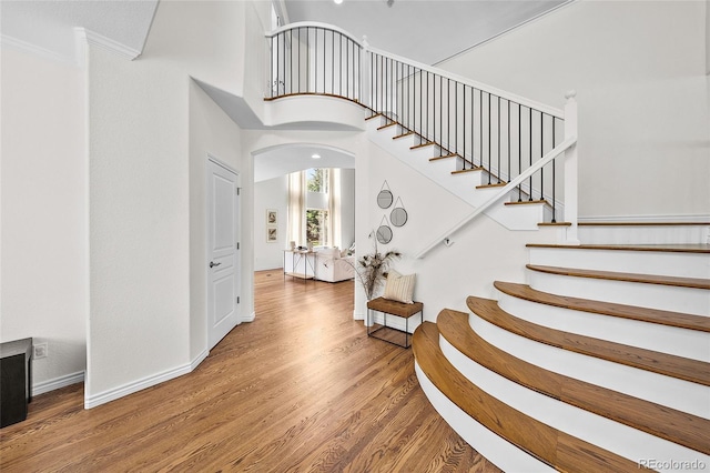10802 W Indore Dr, Littleton, CO 80127 - staircase with arched walkways, ornamental molding, wood finished floors, and baseboards