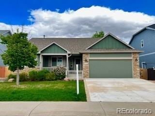 445 Homestead Ln, Johnstown, CO 80534 - view of front facade featuring an attached garage, driveway, covered porch, and stone siding