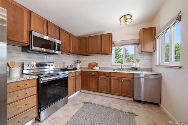 5975 Dover St, Arvada, CO 80004 - kitchen featuring stainless steel appliances, tasteful backsplash, plenty of natural light, and brown cabinets