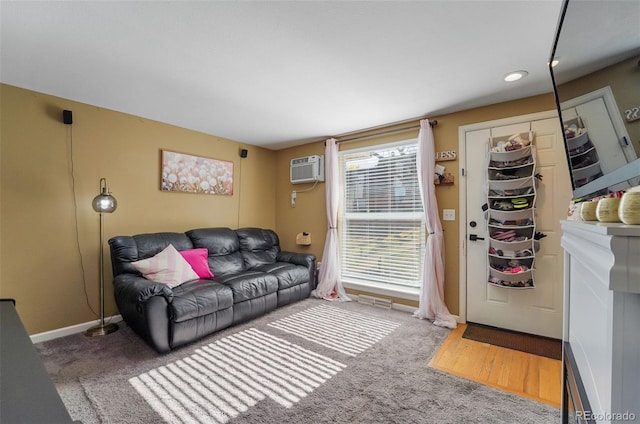 carpeted living area featuring an AC wall unit and baseboards