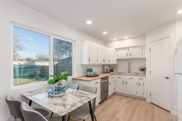 kitchen featuring white cabinetry, sink, dishwasher, light hardwood / wood-style flooring, and butcher block countertops