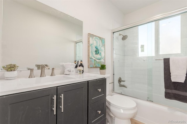 full bathroom featuring vanity, bath / shower combo with glass door, and toilet