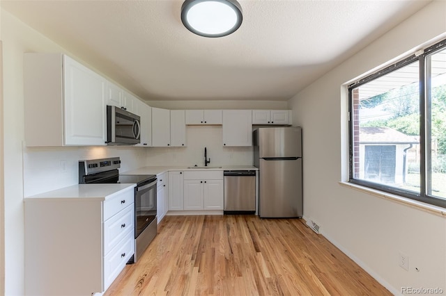 6176 Ammons St, Arvada, CO 80004 - kitchen featuring appliances with stainless steel finishes, light countertops, light wood-style flooring, backsplash, and white cabinets