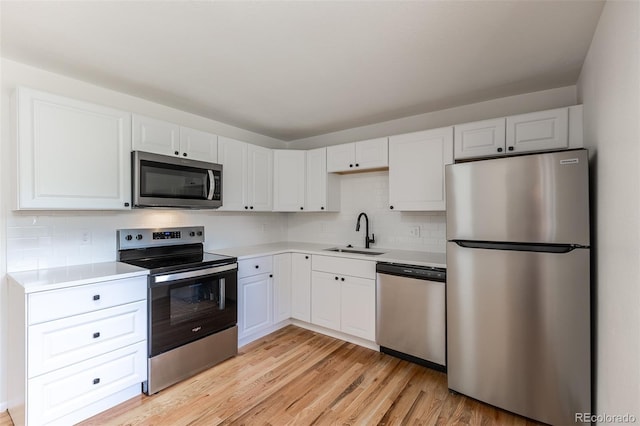6176 Ammons St, Arvada, CO 80004 - kitchen featuring appliances with stainless steel finishes, light wood-style flooring, decorative backsplash, light countertops, and white cabinetry