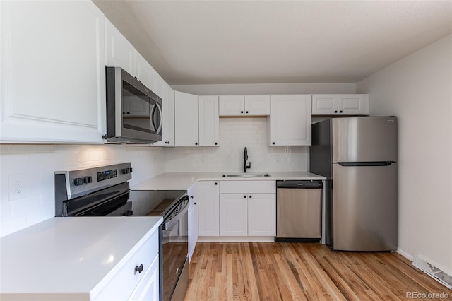 6176 Ammons St, Arvada, CO 80004 - kitchen featuring appliances with stainless steel finishes, light wood finished floors, light countertops, and backsplash