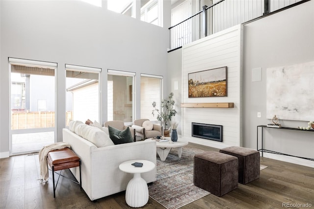 living room with a fireplace, dark wood-type flooring, and a high ceiling