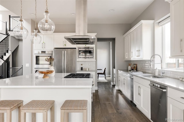 kitchen with sink, appliances with stainless steel finishes, decorative light fixtures, island range hood, and white cabinetry