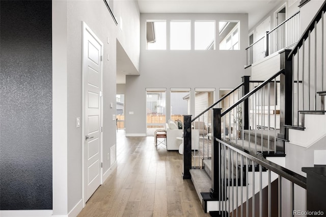 entrance foyer featuring light wood-type flooring and a towering ceiling